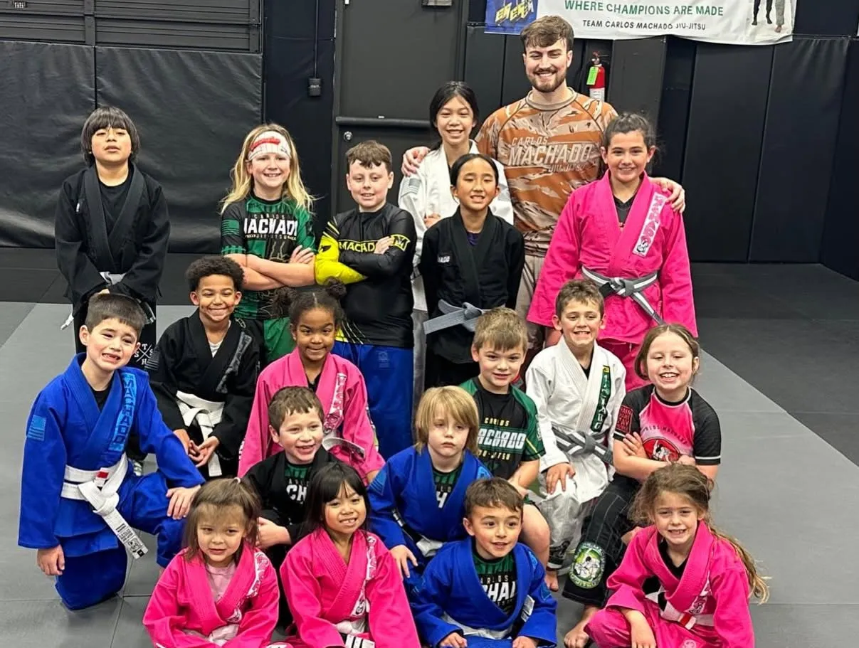 Machado Method students of all ages together in their gis under the Team Carlos Machado banner in Carrollton, TX
