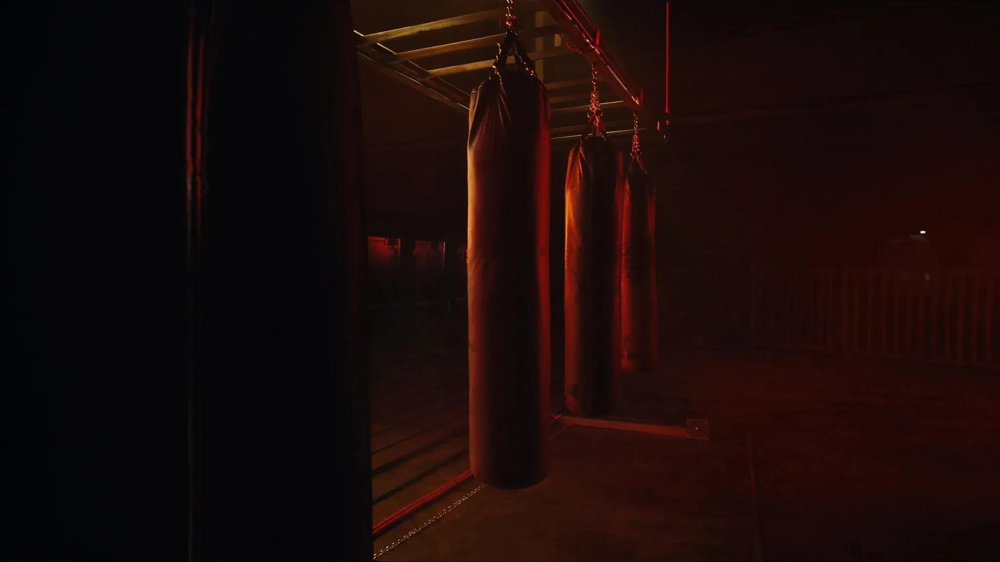 Heavy bags under dramatic red light in a Muay Thai and kickboxing training area